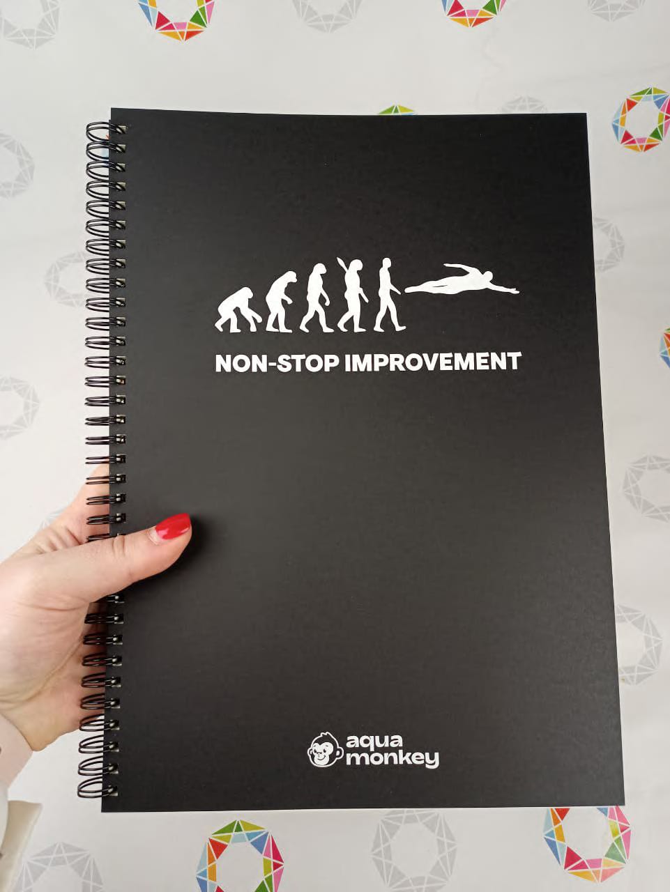 A4 notebook with a black Ispira cover held in hand, white foil logo stamping