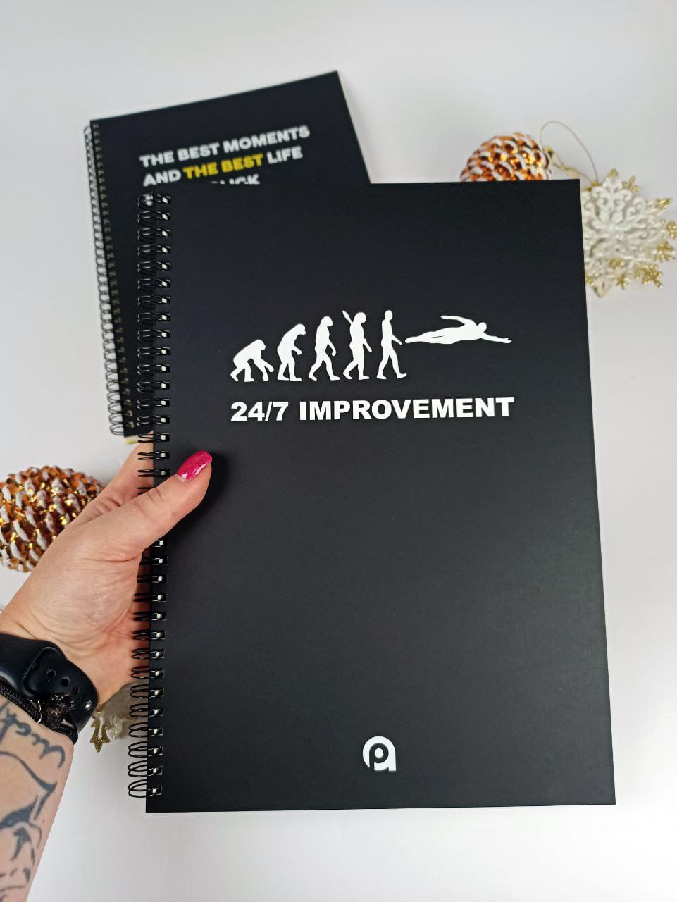 A4 notebook with white foil and a black Ispira cover, in hand