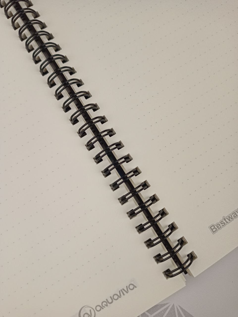 Close-up of the black wire binding and an open spread of the inner block on cream Munken paper 90 gsm