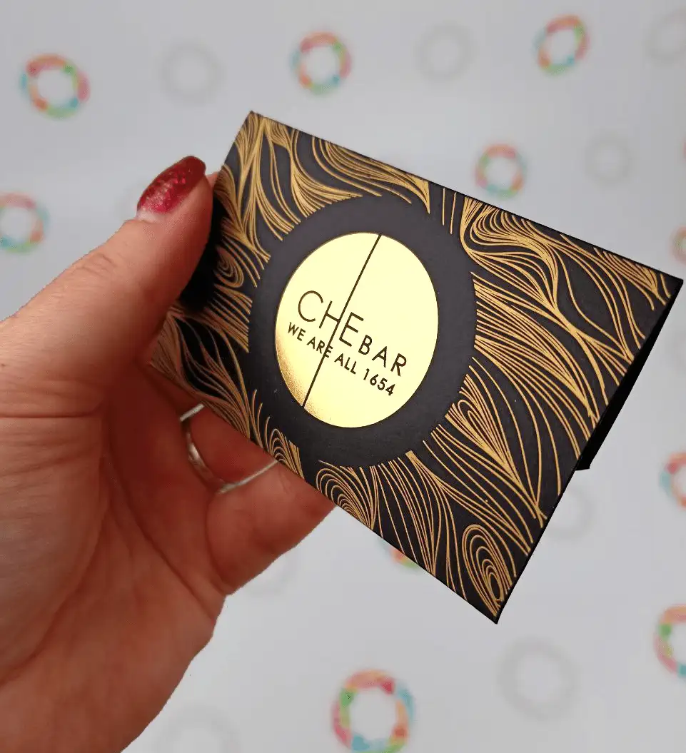 Premium black envelope with gold foil stamping and a bronze pattern, another angle in hand